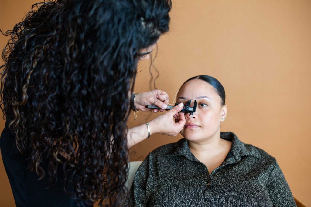 Masa carefully planning the shape of a client’s brows